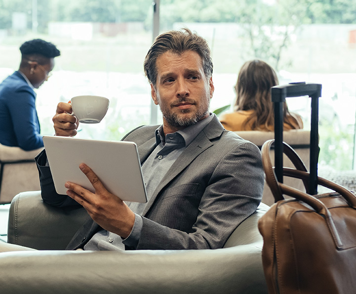 giovane donna con berretto rosso e cappotto beige cammina felicemente per una strada cittadina. Sullo sfondo si intravede un edificio storico con cupola. Elementi grafici circolari blu e turchesi decorano l'immagine.